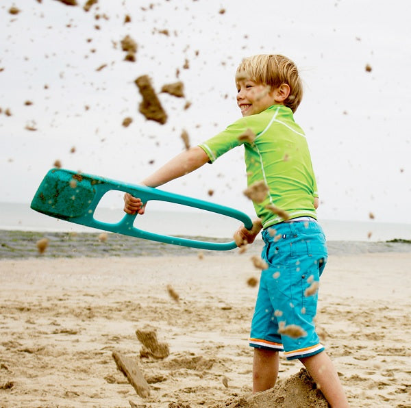 Un enfant joue joyeusement avec des jouets de plage sur une plage.