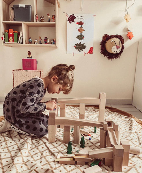 Enfant jouant avec une piste de balle en bois dans la salle de jeux pour enfants.