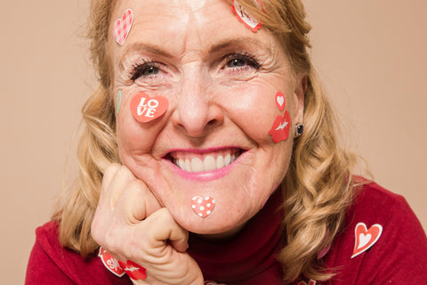 Closeup of older woman smiling joyfully with heart stickers on her face