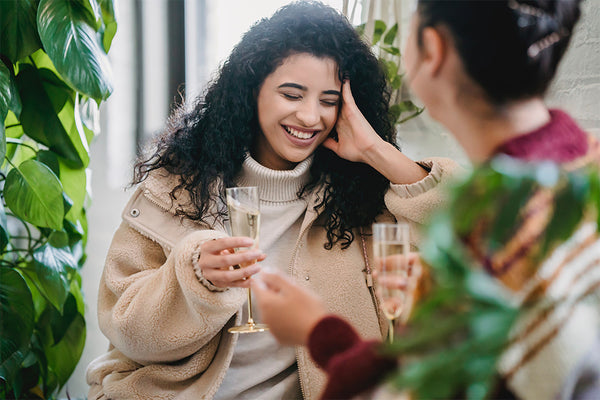 Two women talking to each other as one women sheepishly has eyes closed but a smile on her face. Photo by Julia Larson from Pexels