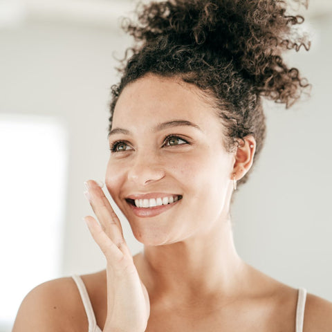 woman smiling while doing her daily skin routine