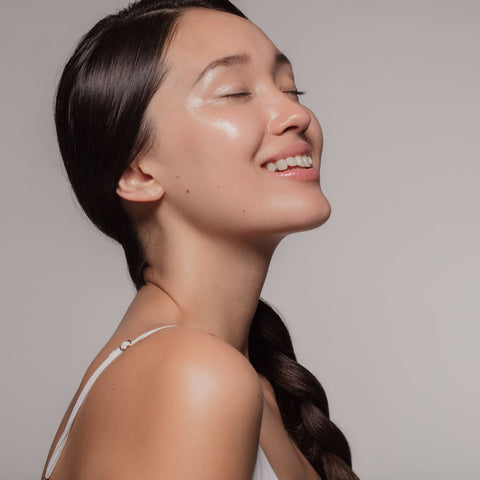 woman with glowing skin smiling with her eyes closed