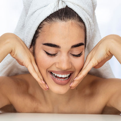 woman wearing towel on her head while holding her face in her hands