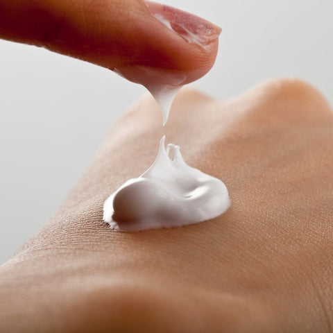 close up of someone applying body butter to the back of their hand