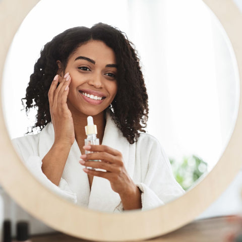 smiling woman putting serum on her face