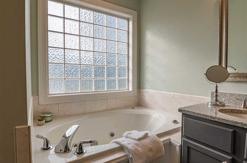 Bathroom with bath tub, sink, towels, and frosted window