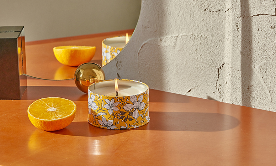 Orange half and lit tin candle on table