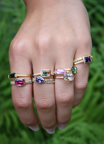 hand with colorful gemstone ring stacks