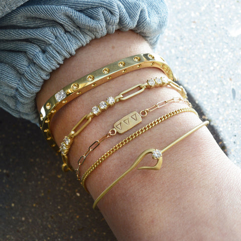 close up of gold and diamond permanent jewelry bracelets with engraved stamps greek letters tri delta