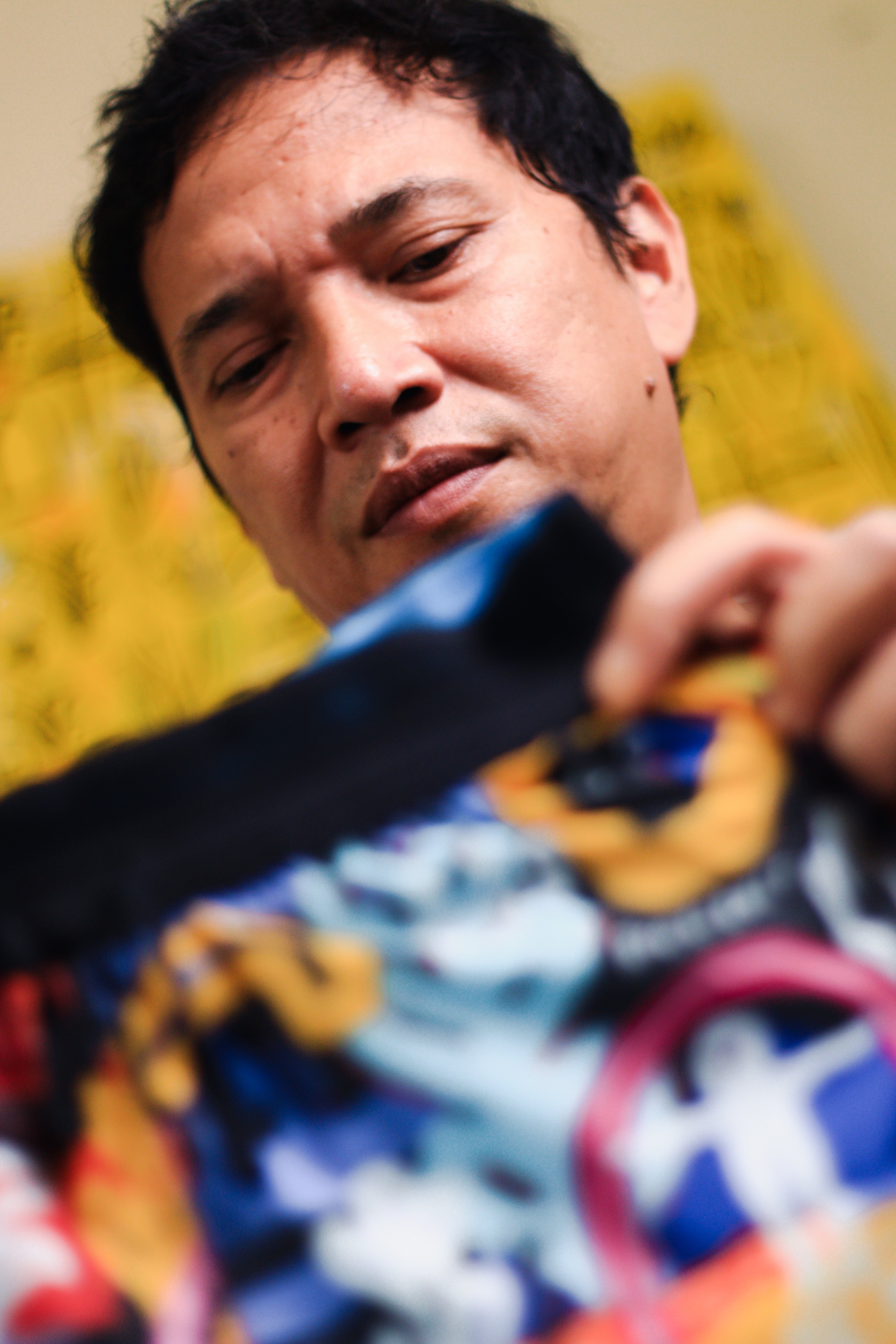 Artist Soni Irawan holds up a pair of shorts featuring the colorful Mt. Merapi print