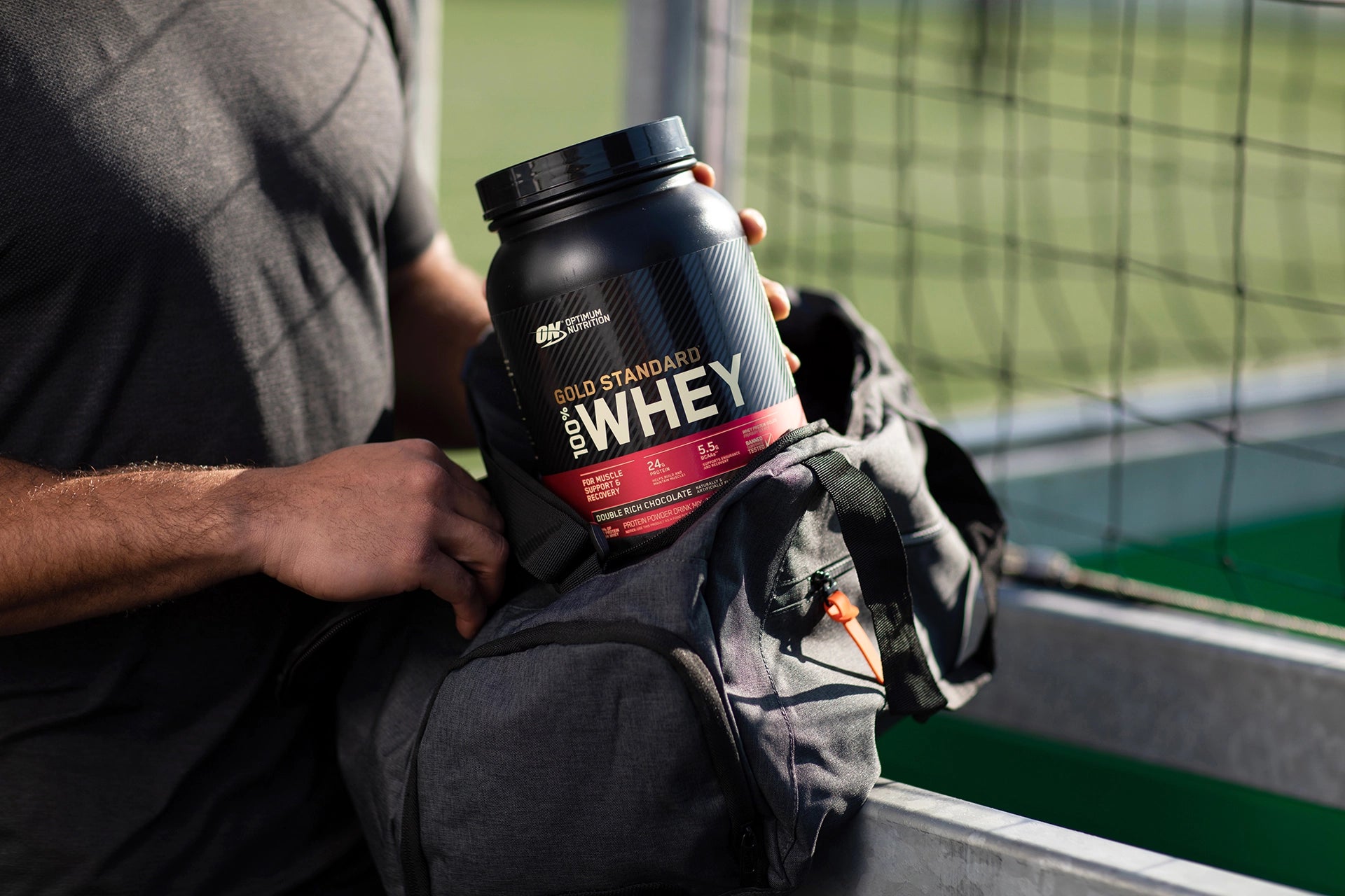 Guy pulling Optimum Nutrition Gold Standard Whey out of a gym bag