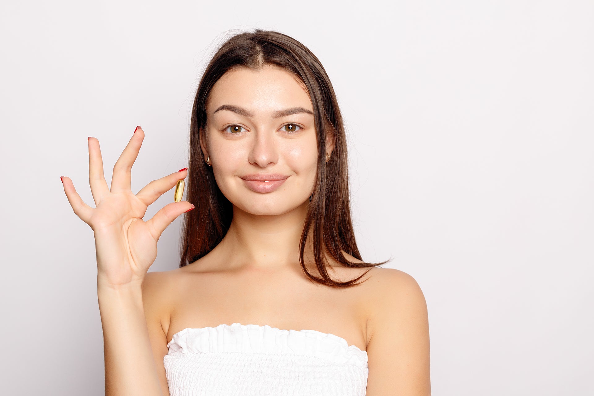 Smiling Young Woman Holding Fish Oil Pill