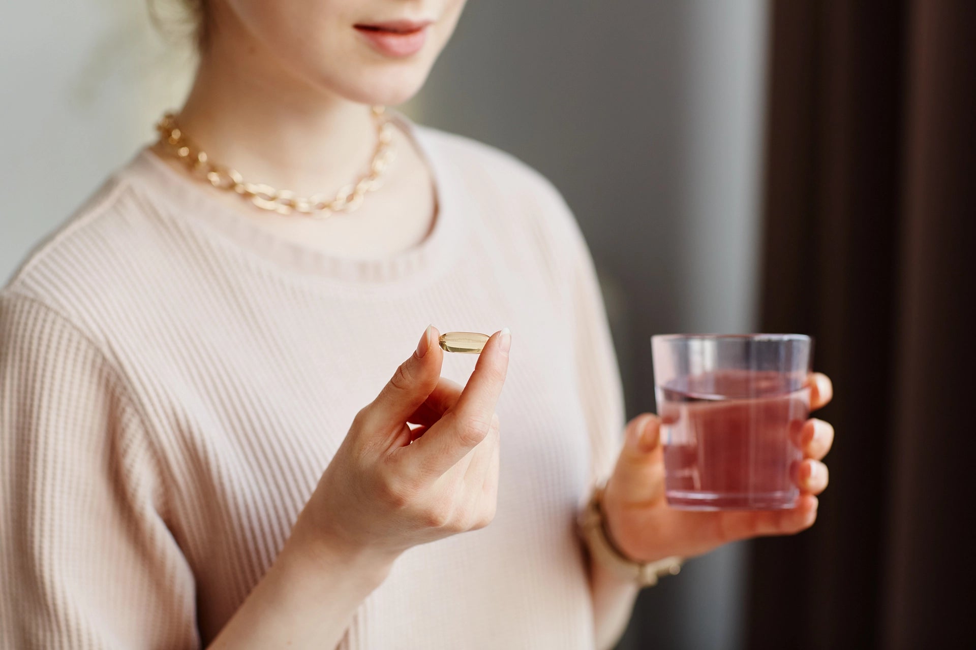 Woman taking Vitamin Capsule with a glass of water