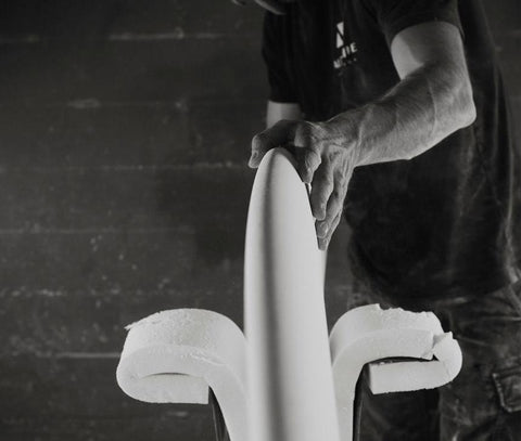 A shaper using a planer to sculpt a foam blank into a surfboard
