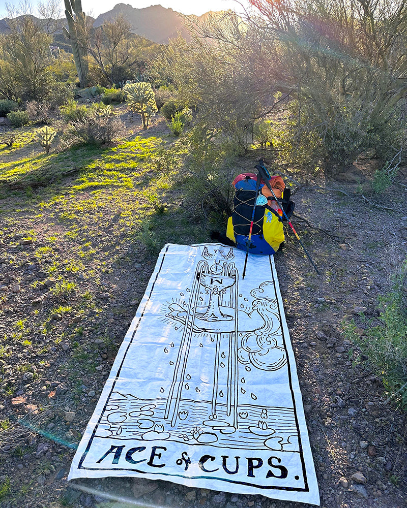 tyvek footprint with a tarot card "Ace of Cups" draw on it in the desert.