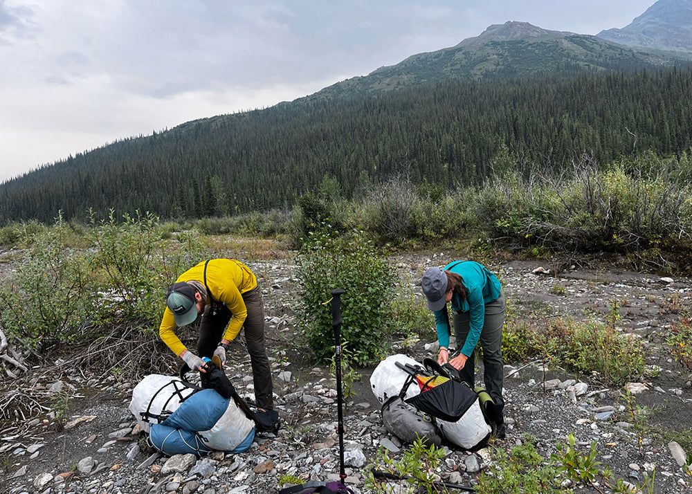 Superior Wilderness Designs founder packing up their packs near a mountain