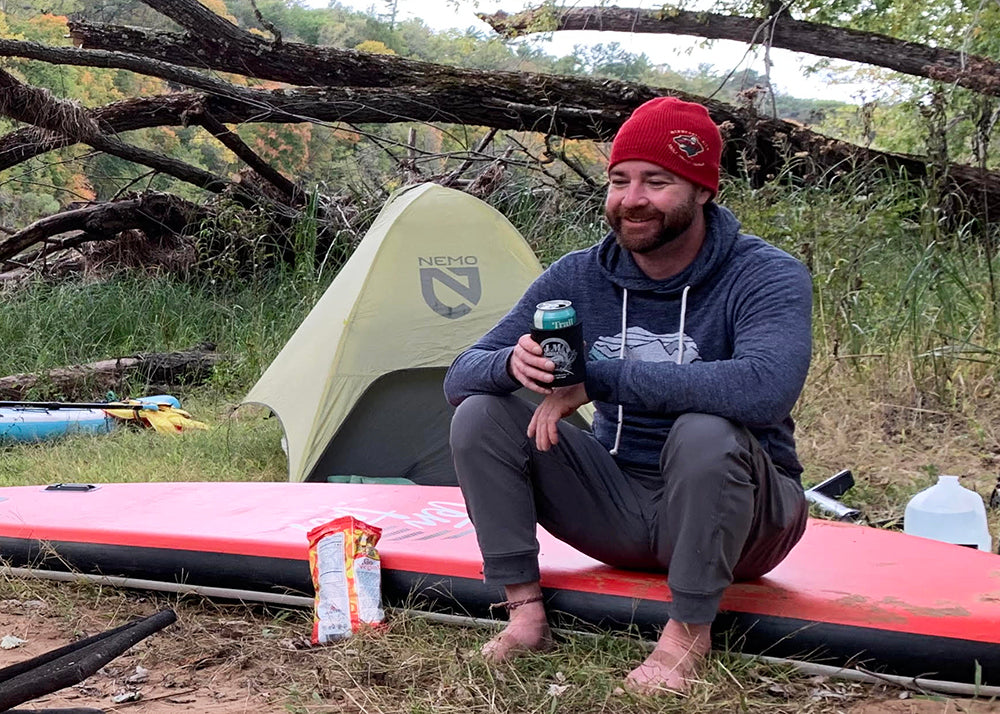 nemo tent behind a guy sitting on a paddleboard smiling