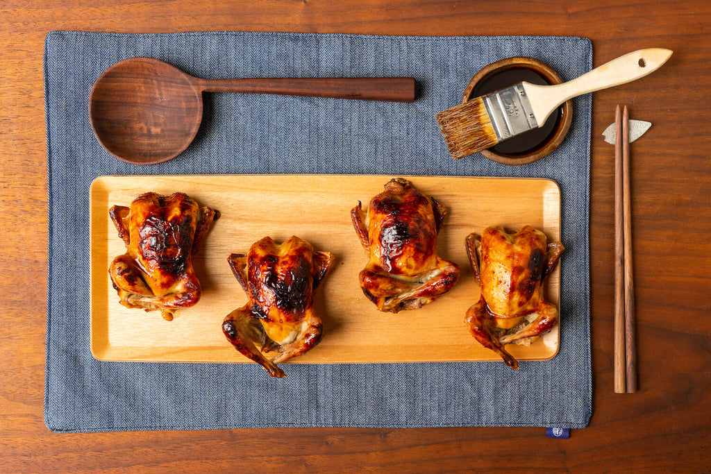 Four glazed quails on serving board.