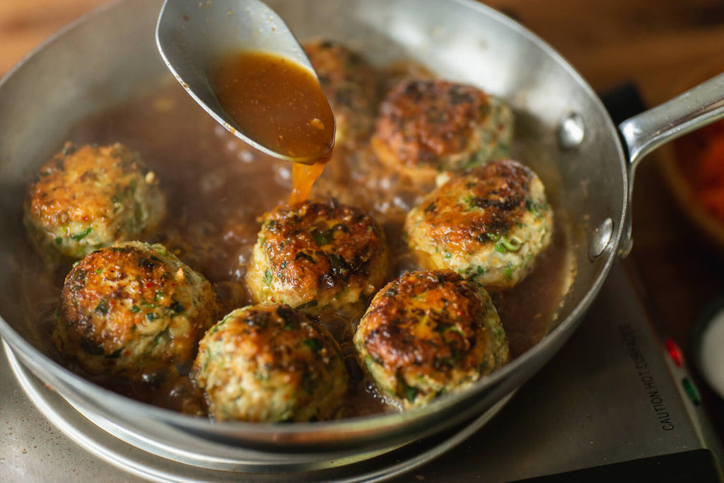 Meatballs cooking in Nong's sauce and chicken stock.