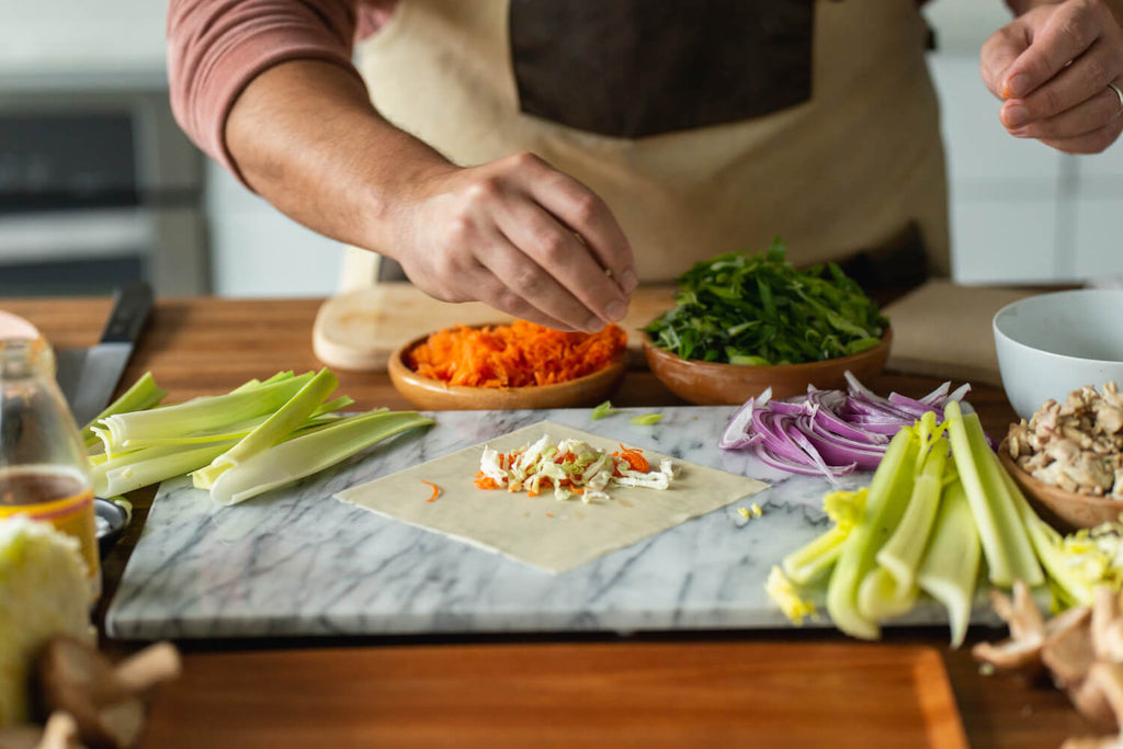 Chef adding ingredients to an unrolled egg roll. 