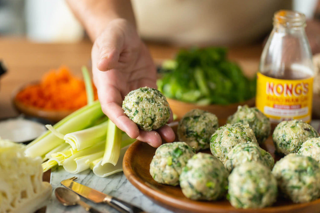 Chef picking up raw meatball.