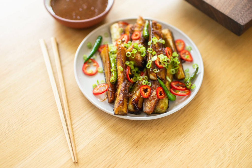Stir-fried eggplant pictured with chopsticks.