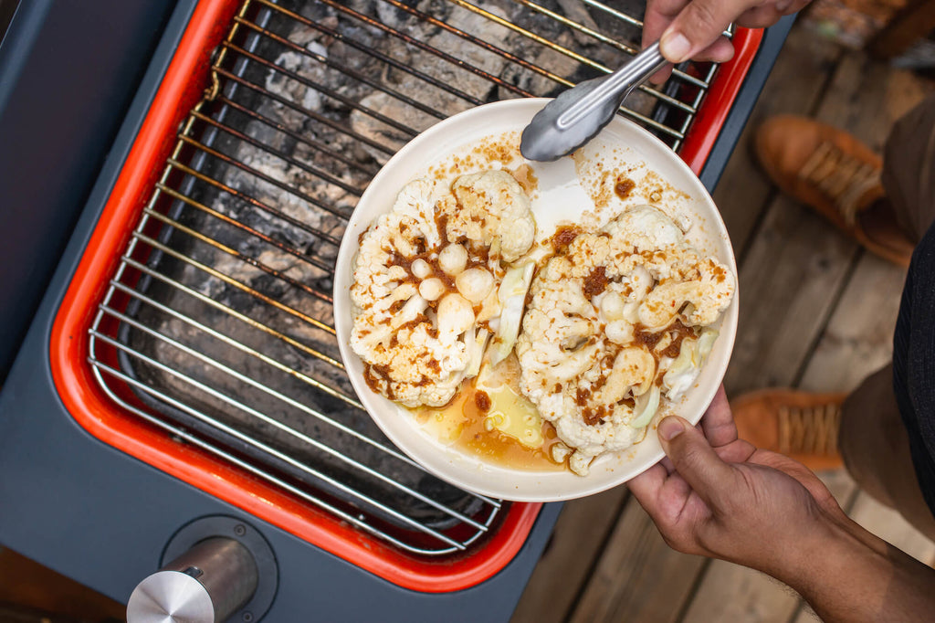 Putting marinated cauliflower steaks on the grill.
