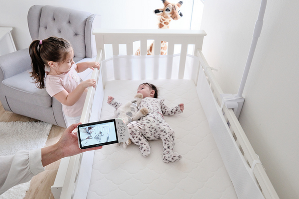 Babysense Maxview viewed by parent that shows a baby in their cot a sibling looking over the cot at the baby