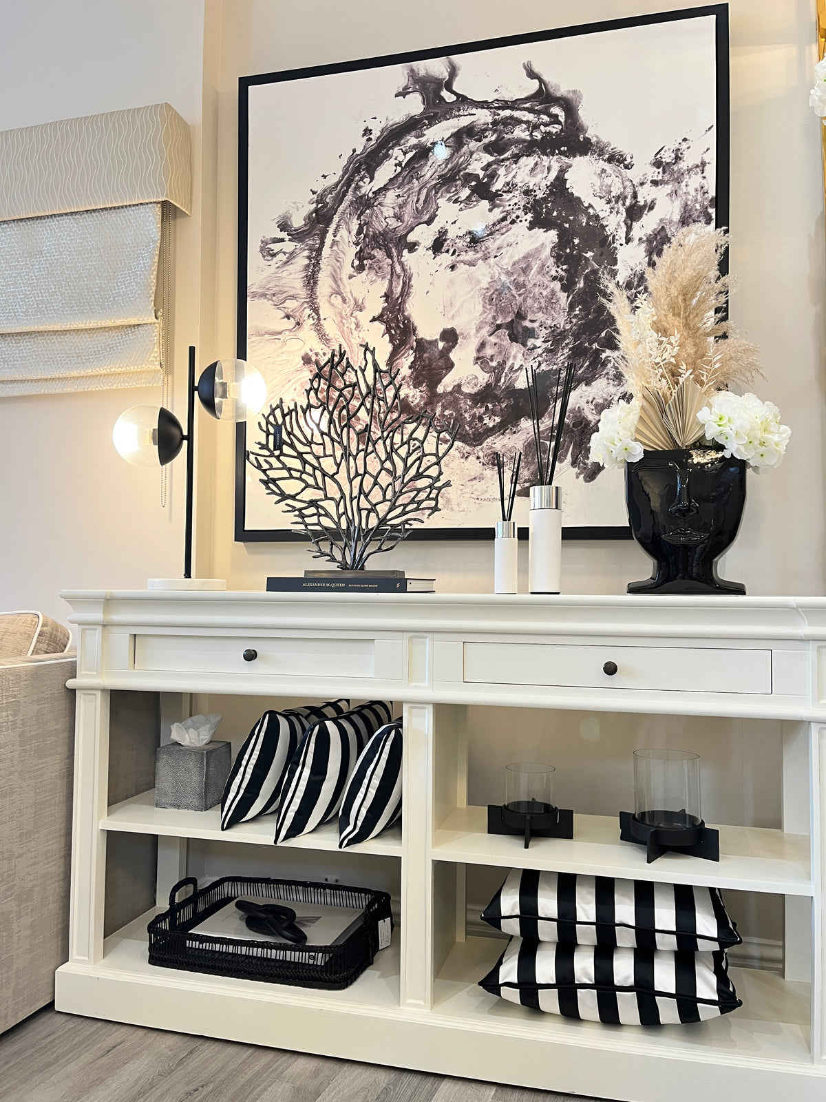 Monochrome home interiors. White console table with black home accessories, pampas grass, rattan chair and coffee table books