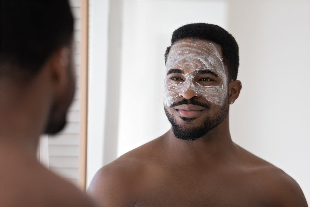 Mann mit Gesichtsmaske schaut in den Spiegel.