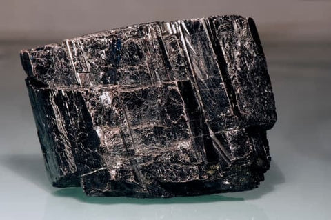 A powerful Black Tourmaline crystal, showcasing its deep black color and unique striations, symbolizing grounding, protection, and the absorption of negative energy.