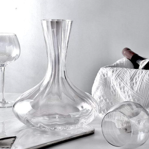 Crystal wine decanter next to two crystal wine glasses.