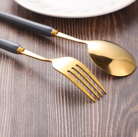 Golden fork and spoon next to each other on a dark wooden table.