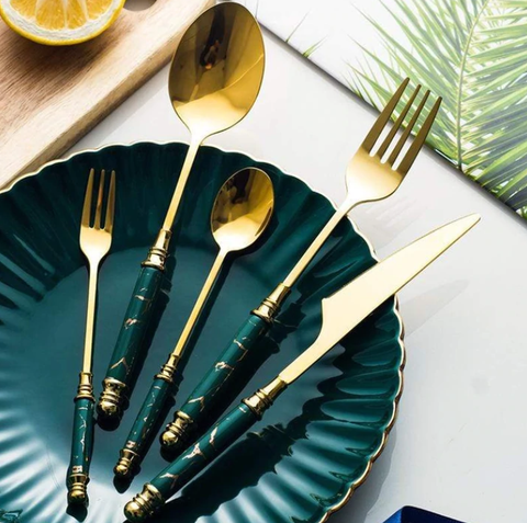 Cutlery Sets | Golden cutlery set with marble handle parts neatly laid on a dark green plate.