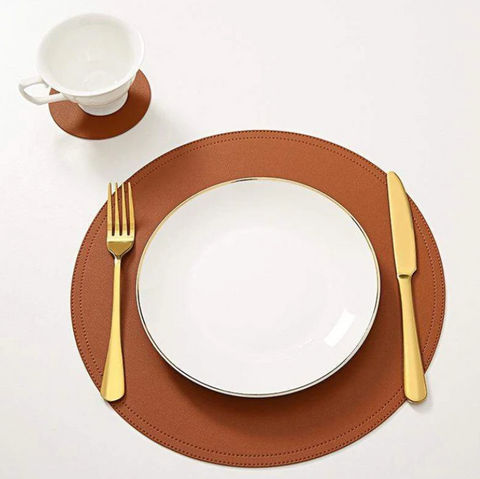 Placemats | A plate, cup, fork and knife placed on top of a brown leather placemats.
