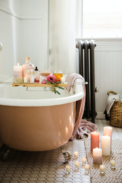 bathtub with a caddy and scented candles on the floor 