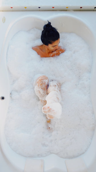 woman having a relaxing bubble bath in a white bathtub