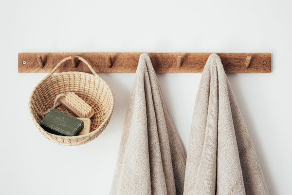 two beige towels hanging from wooden hooks