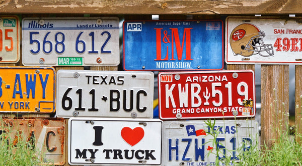 assorted American license plates hung on a wooden fence