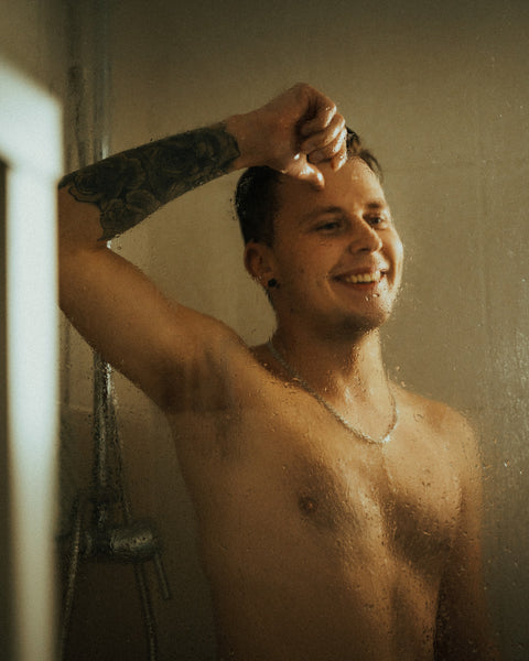 smiling man with tattoo inside the shower