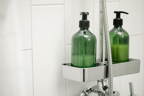 two green dispensers on shower system shelf 