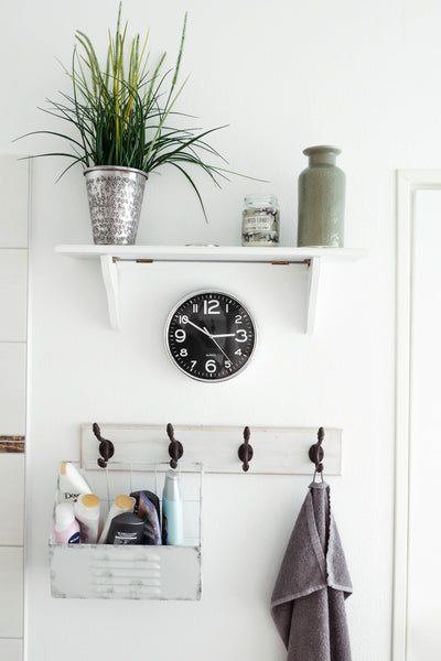 white bathroom wall with floating shelf and towel hooks 