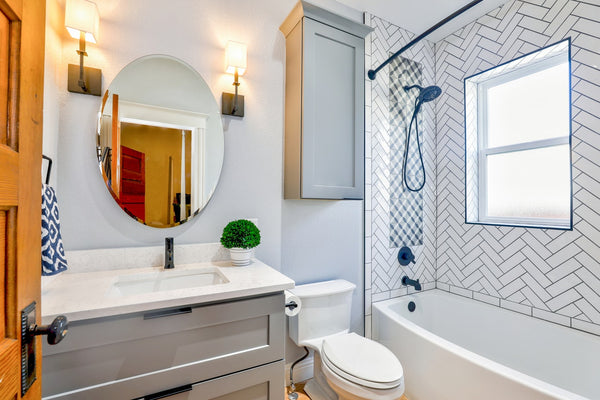 tiny white bathroom with oval vanity mirror and bathtub