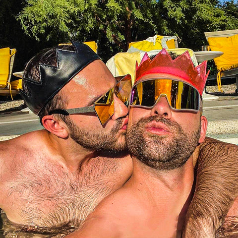 2 gay men kissing wearing pink and black crowns