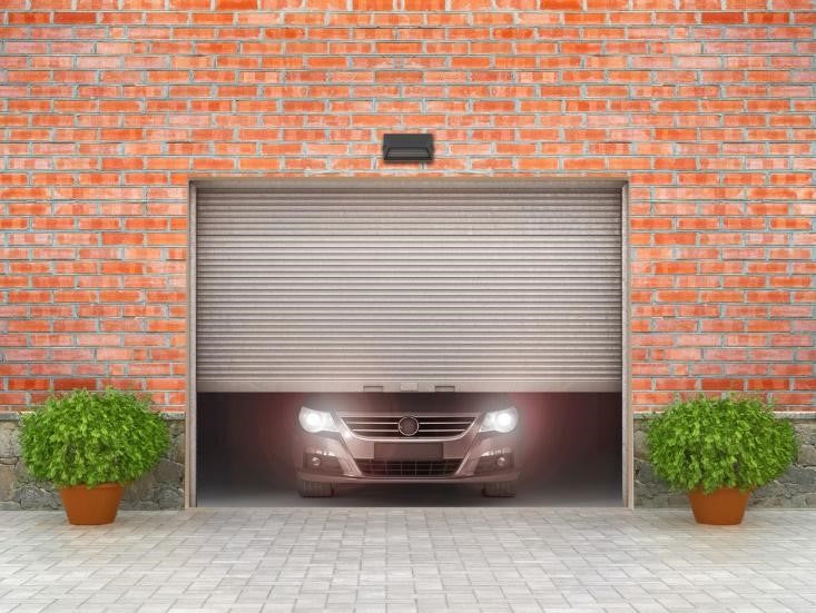 Car behind a steel garage door of a brick house