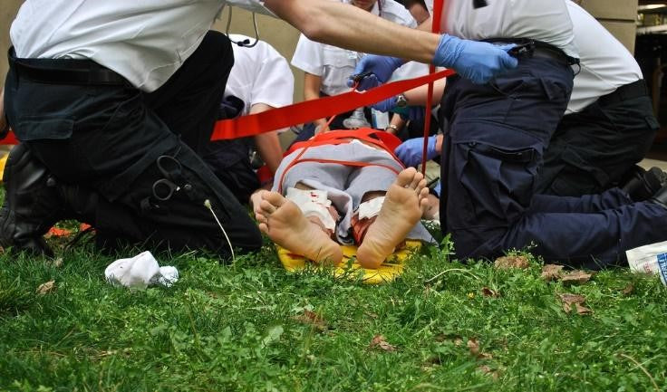 EMT personnel kneeling on the ground while helping a person in emergency