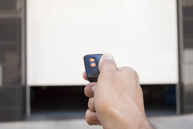 Hand pressing a remote control to open garage door