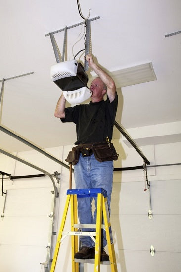 Man standing on a ladder to fix a garage door opener