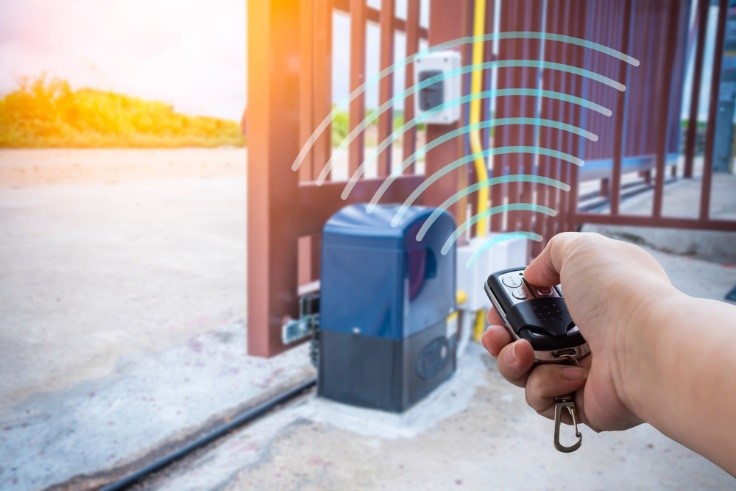 Person holding a remote control sending signal to gate opener