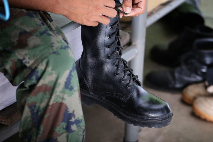 Soldier tying bootlaces of black combat shoes